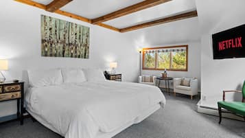 A bedroom with a large bed, a TV mounted on the wall, a window with a view, and a painting on the wall.