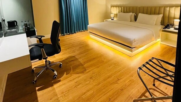 A modern hotel room with a large bed, a desk with a chair, and a wardrobe. - Alsltanah Jazan Hotel (Jizan)