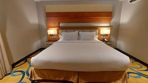 A hotel room with a large bed, two bedside tables with lamps, a wooden headboard, and a patterned carpet. - Alsltanah Jazan Hotel (Jizan)