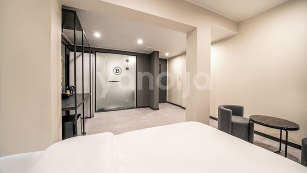 A modern hotel room with a large bed, a small round table, and a seating area with two chairs. - BROWN-DOT HOTEL (Busan)