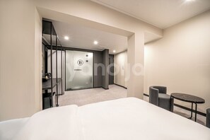 A modern hotel room with a large bed, a small round table, and a seating area with two chairs. - BROWN-DOT HOTEL (Busan)