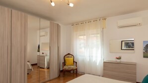 Un dormitorio con un espejo grande, un armario de madera, una silla, una mesita de noche y una cama.