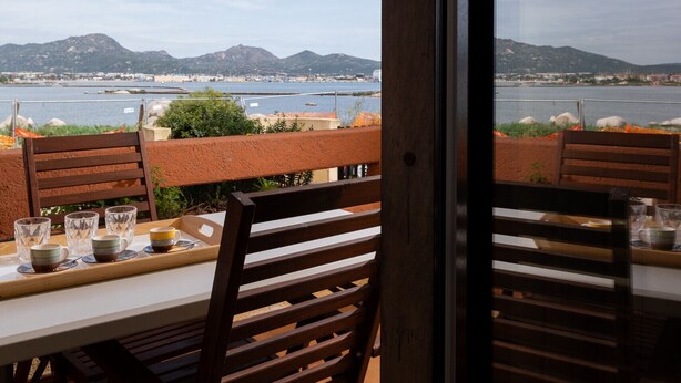 Comedor con una mesa para dos, con vistas a un cuerpo de agua y colinas distantes.