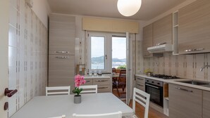 Una cocina moderna con armarios blancos, un comedor con mesa y sillas, y vistas por la puerta abierta.