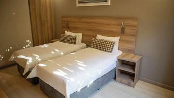 A double bed with a wooden headboard, two bedside tables, and a small wooden shelf.