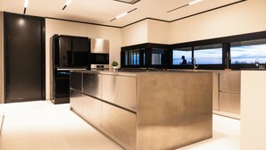 Una cocina moderna con electrodomésticos de acero inoxidable, una isla grande y vistas al exterior a través de las ventanas.