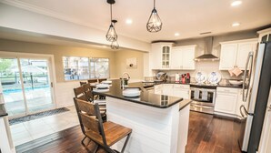 A modern kitchen with a central island, white cabinetry, and a view of a swimming pool. - Resort-Style Canal Home w/ Pool & Putting Green - Baywatch (Apollo Beach)