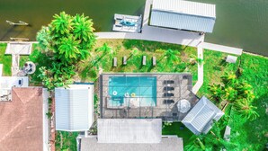 An aerial view of a property with a swimming pool, outdoor seating, and a dock. - Resort-Style Canal Home w/ Pool & Putting Green - Baywatch (Apollo Beach)