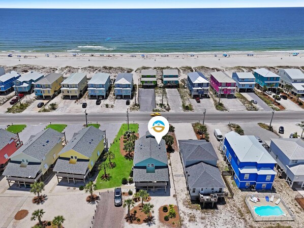 A coastal residential area with houses, a road, and a beach.