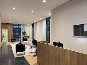 Un hall d’hôtel moderne avec un comptoir d’accueil, un espace salon et de grandes fenêtres.