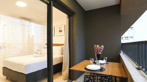 Een hotelkamer met een bed, een eettafel met stoelen en een balkon met een leuning.