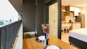 Een moderne hotelkamer met een balkon, een zithoek met een tafel voor twee en een kitchenette op de achtergrond.