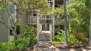 Un edificio residenziale a più piani con una scala centrale, circondato da vegetazione e un giardino curato.