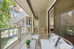 Un balcon avec une balustrade blanche, des meubles en osier et une plante en pot.