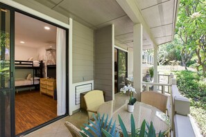 A room with a bed, a TV, and a window overlooking a garden. - Newly Remodeled! Wailea 2BR | Walk to Beach | A/C | Family-Friendly (Kihei)
