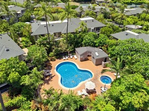 Un barrio residencial con varias casas, una piscina y abundante vegetación.