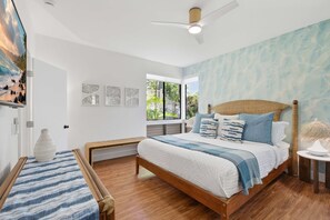 A bedroom with a wooden bed, a ceiling fan, and a view of the outdoors.