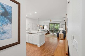Una cocina moderna con armarios blancos, una isla central y un comedor con una mesa redonda.