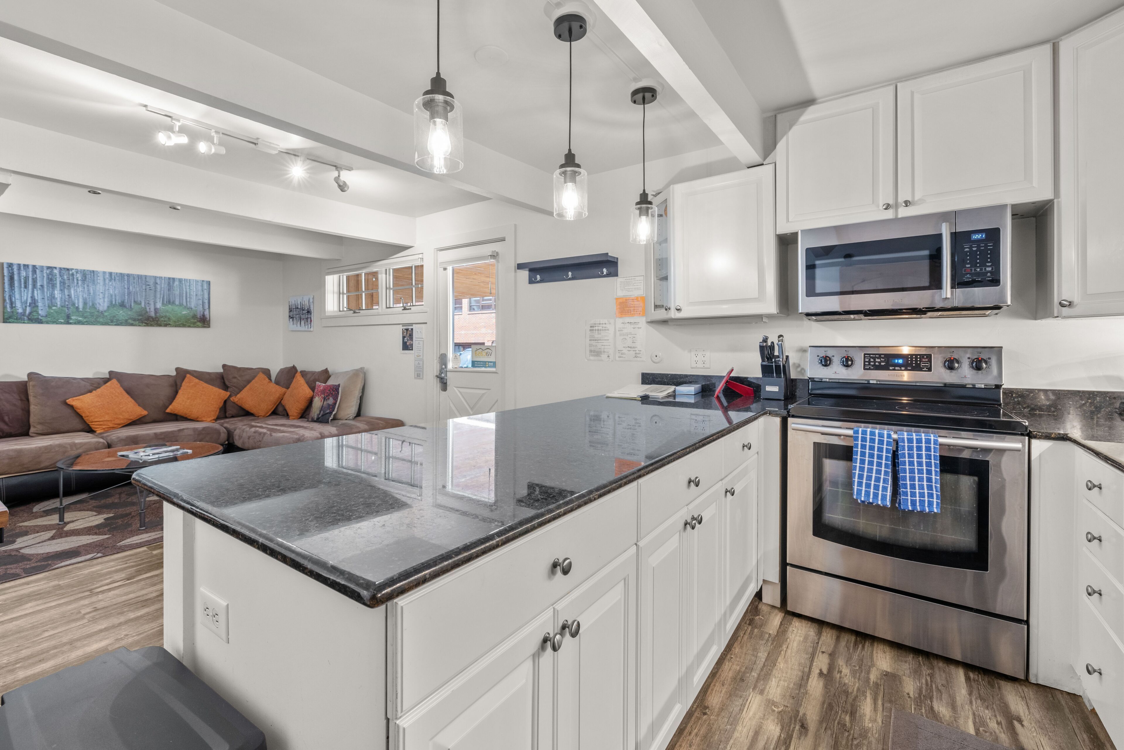 A modern kitchen with white cabinets, stainless steel appliances, and a large island.