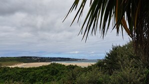 A coastal landscape with a beach, vegetation, and a cloudy sky. - C14 Gwelmore, Riviere Towans (Hayle)