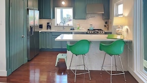 Una cocina moderna con armarios color turquesa, una isla central con taburetes de bar, una estufa y un fregadero.