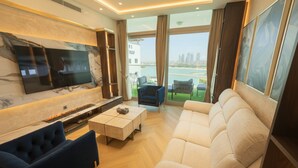 A modern living room with a flat-screen TV, a fireplace, a sofa, and a view of the city. - Highend Azure Stay In Palm Jumeirah (Dubai)