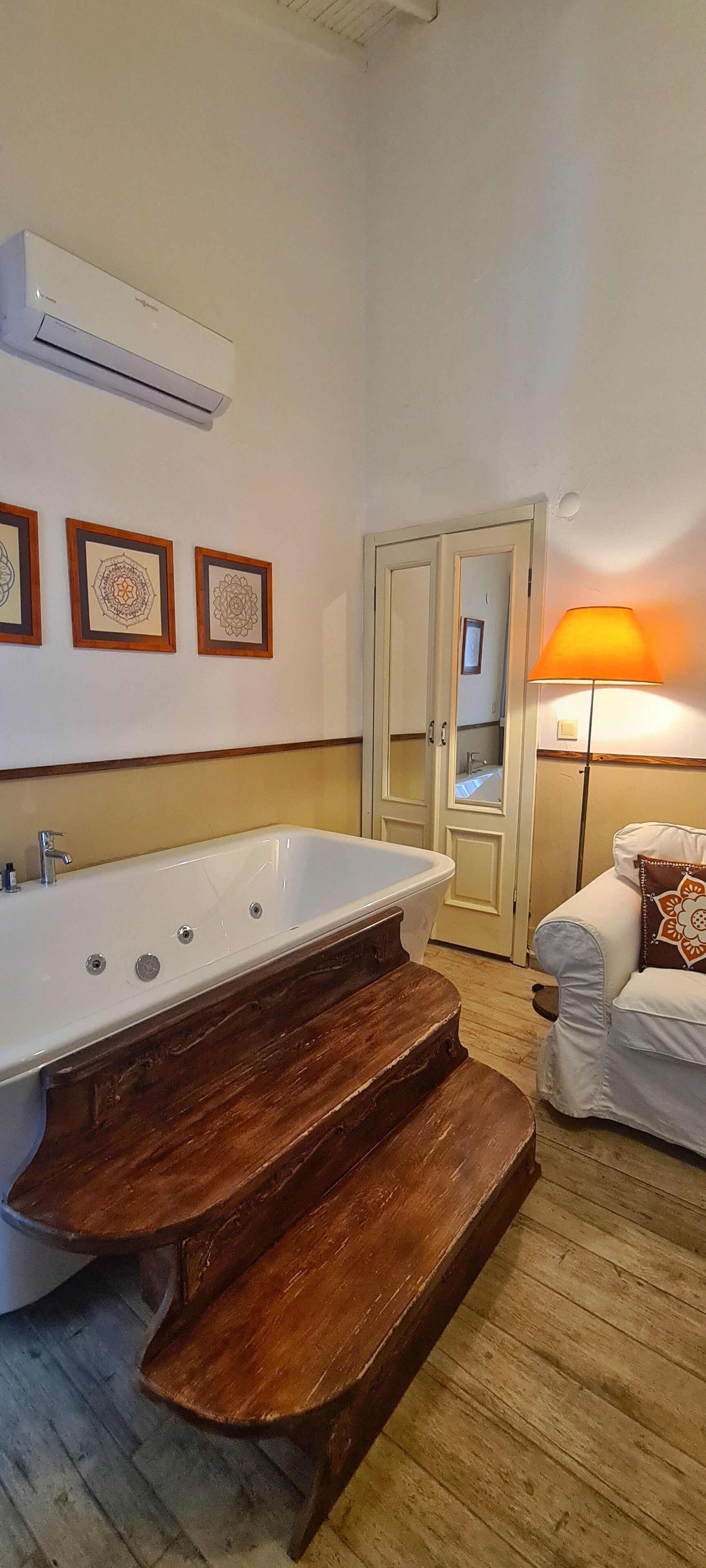 A bathroom with a freestanding bathtub, wooden steps, a white sink, and a mirror.