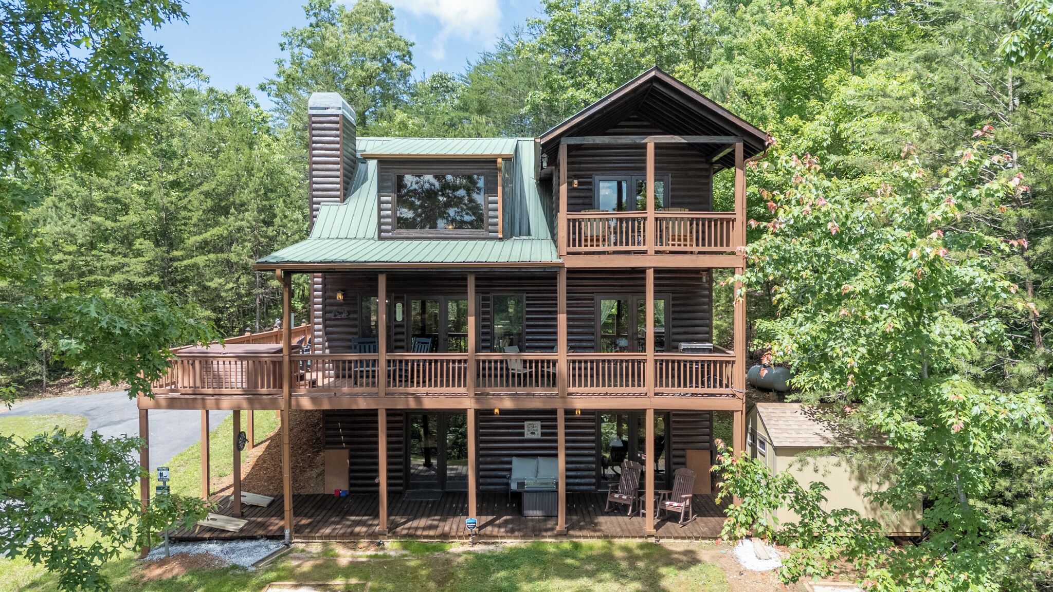 Une cabane en rondins à deux étages, dotée d’un balcon et entourée d’arbres.