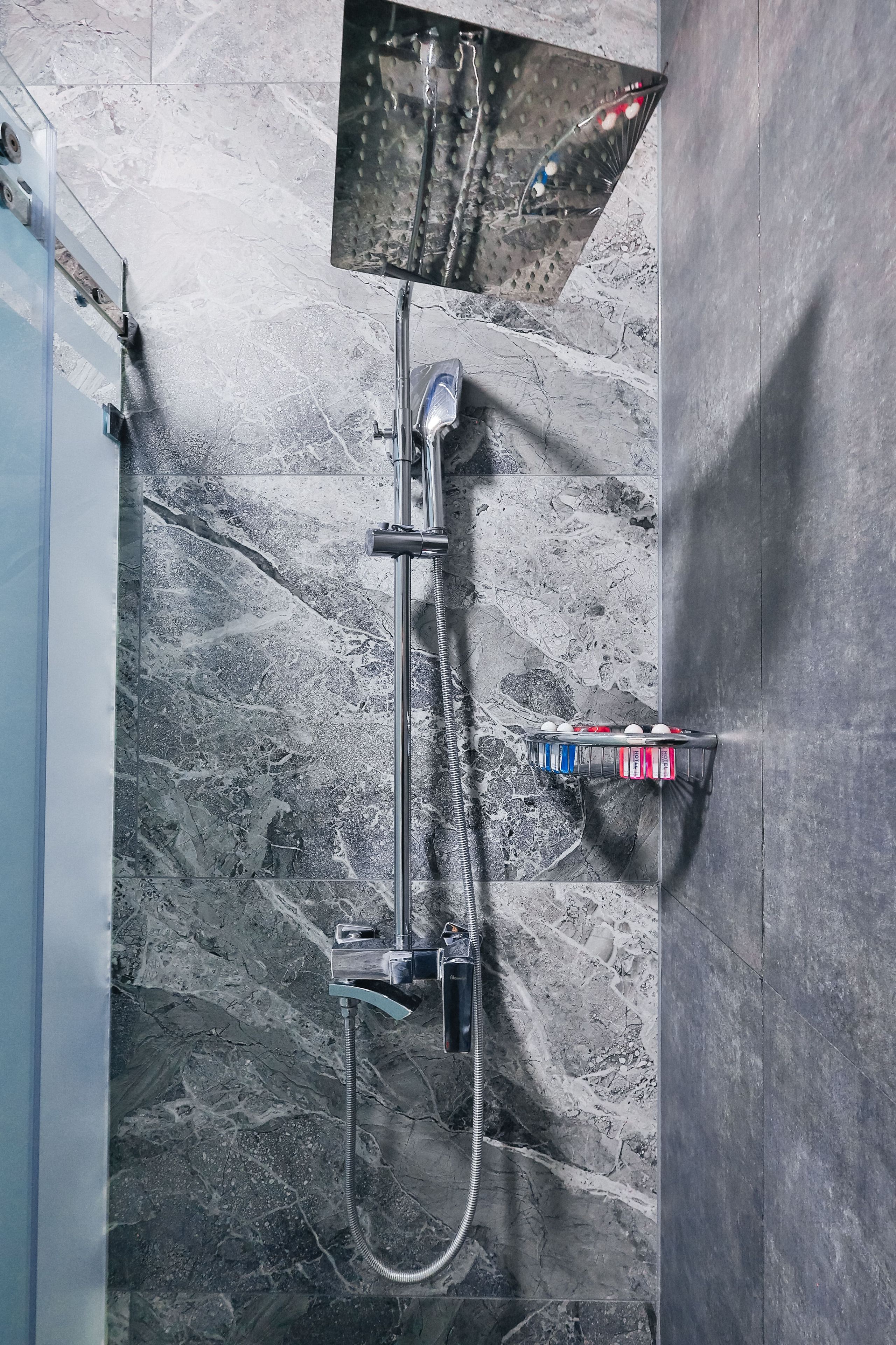A modern shower with a handheld showerhead and a wall-mounted control panel.