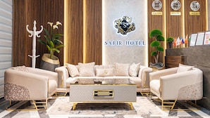 A modern lobby with a sofa set, a coffee table, and a reception desk. - Safir Hotel  (Fergana)