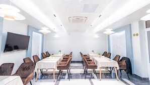 A conference room with a long table, multiple chairs, a flat-screen TV, and ceiling lights. - Safir Hotel  (Fergana)