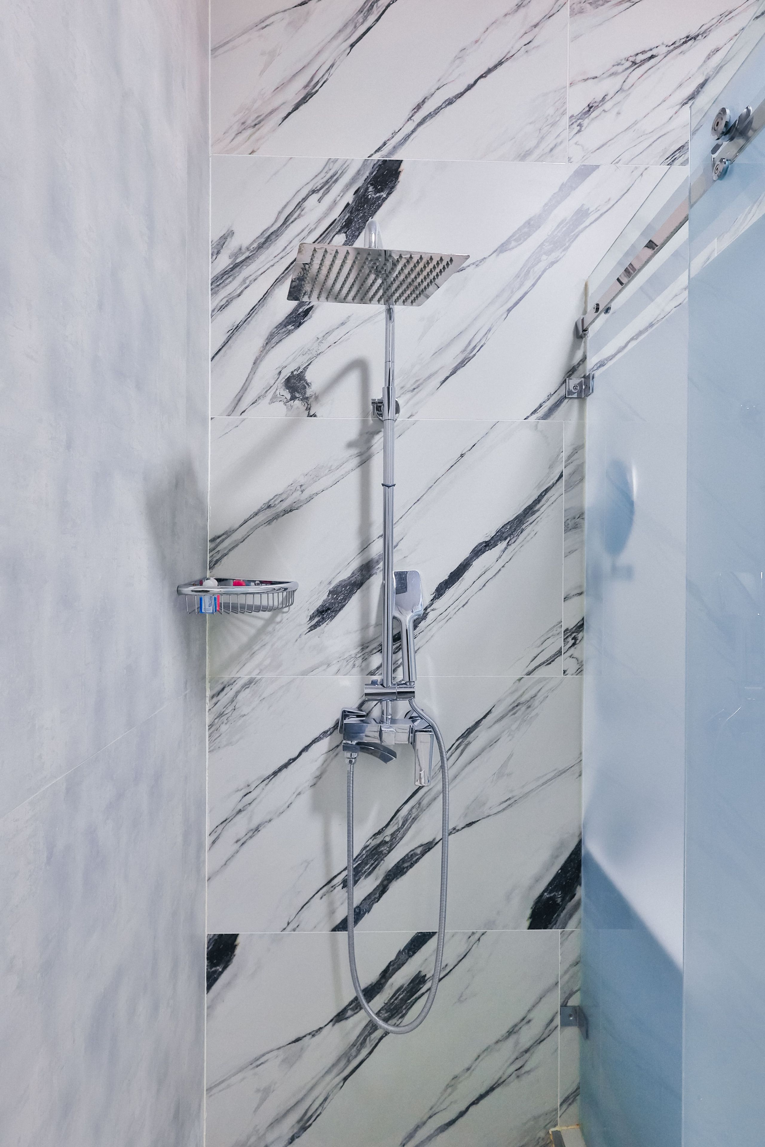 A bathroom with a shower, a towel rack, and a mirror.