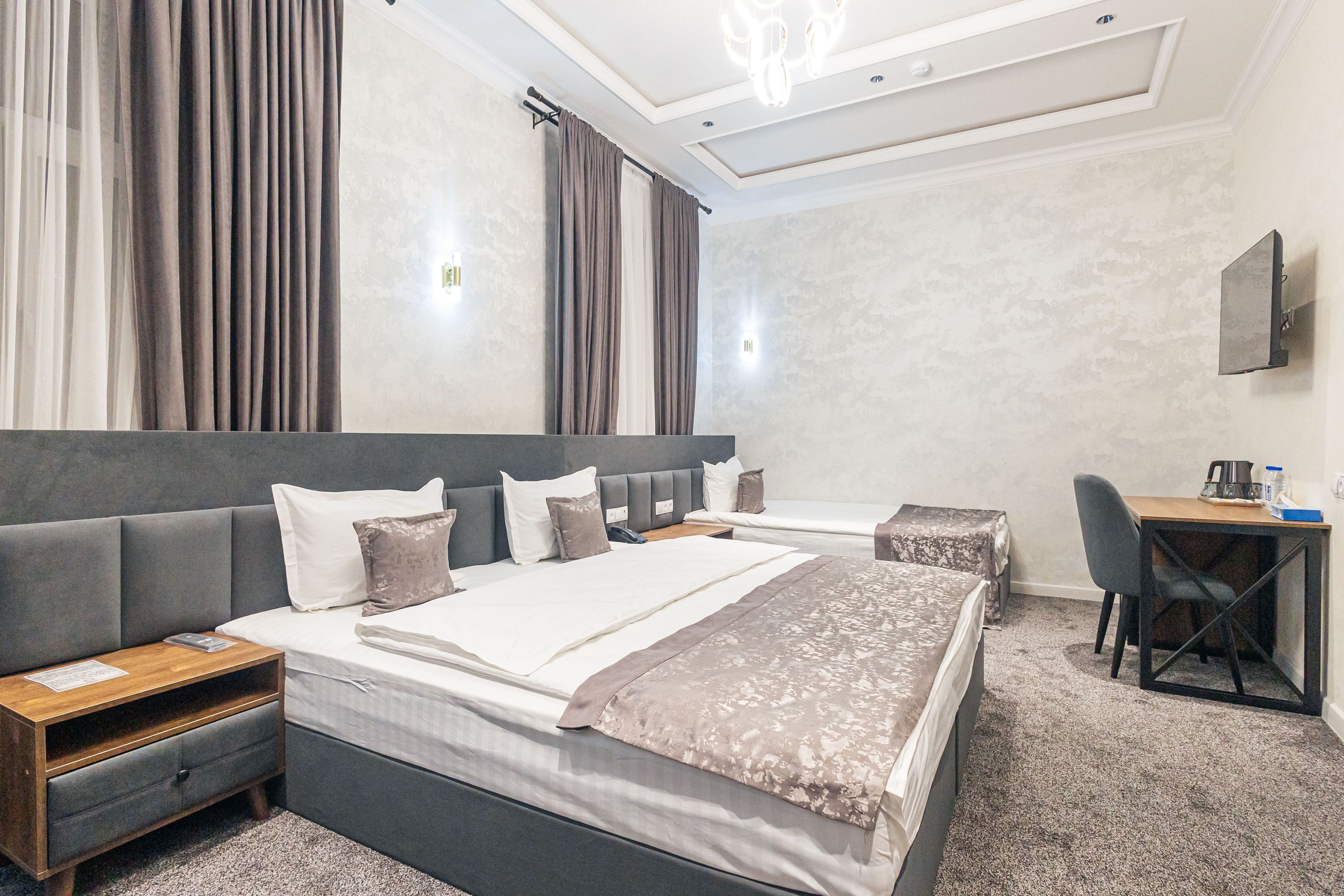A modern hotel room with a large bed, a desk, and a chair.