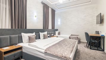 A modern hotel room with a large bed, a desk, and a chair.