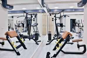 A gym with mirrored walls, exercise equipment, and a wooden floor. - Safir Hotel  (Fergana)