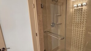 Eine Duschkabine mit Glas, ausgestattet mit einer Handbrause und einer Glastür.