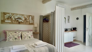A bedroom with a bed, pillows, a painting, a wardrobe, and a bathroom visible through an open door. - Sam’s cottage, a peaceful Provencal Retreat, minutes from famous Thoronet Abbey. (Le Thoronet)