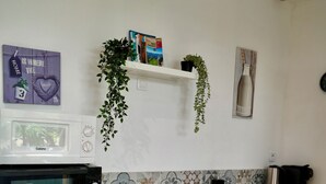 A compact kitchen with a microwave, oven, and a sink. There is a shelf with a plant and a few books. - Sam’s cottage, a peaceful Provencal Retreat, minutes from famous Thoronet Abbey. (Le Thoronet)