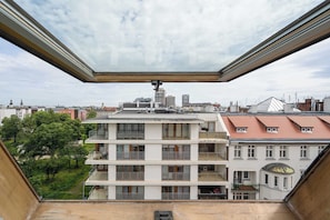 Un immeuble à plusieurs étages doté de balcons, un ciel dégagé et une vue sur d’autres bâtiments en arrière-plan.