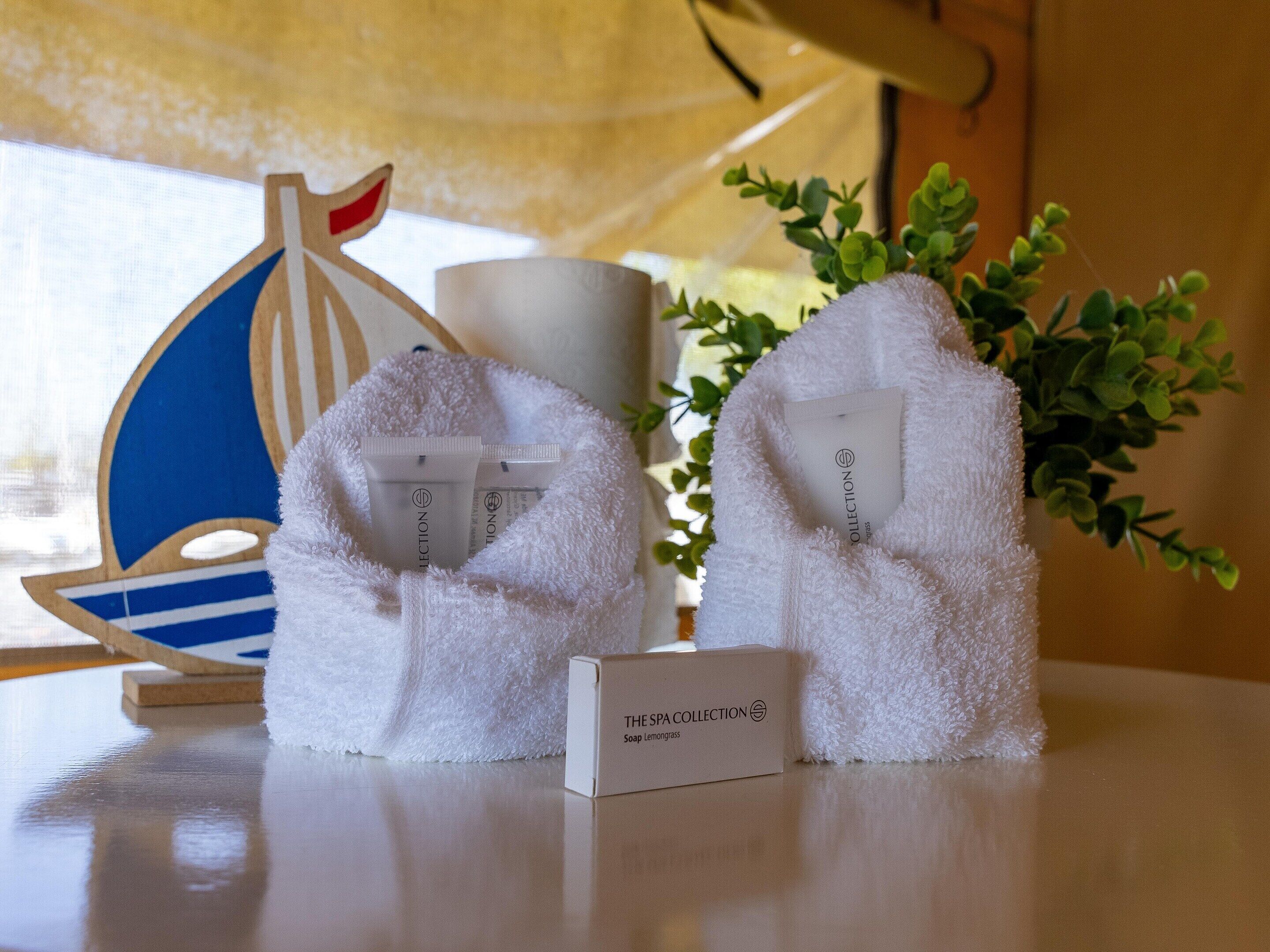 A spa collection sign, two white towels, a wooden ship decoration, and a potted plant.