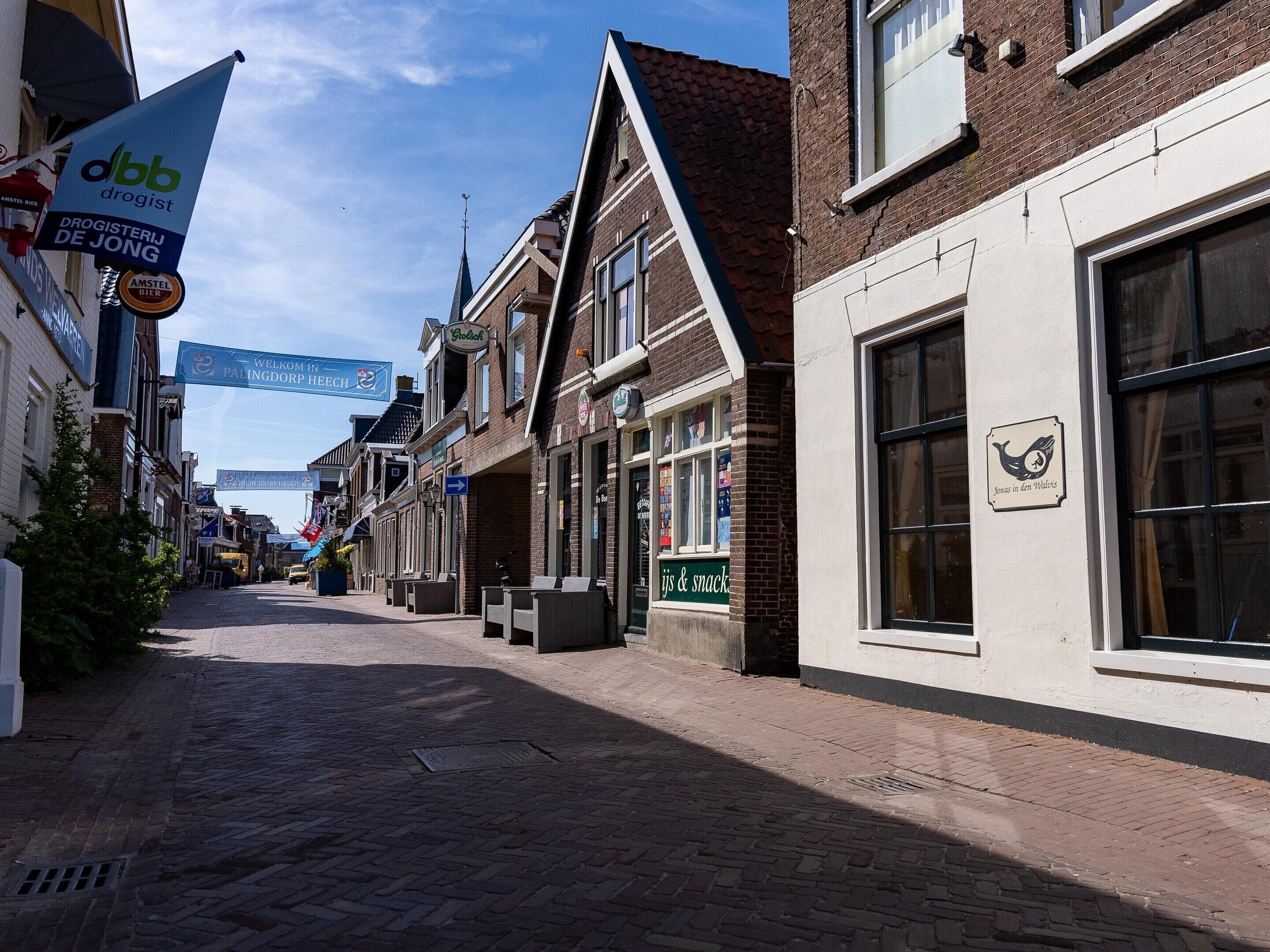 A narrow cobblestone street lined with traditional European buildings, some with visible signage for local businesses.