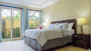 A bedroom with a bed, bedside tables, a lamp, and a view of the outside. - Star Tree- 2 Bedroom Condo 10 mins to New Kingston (Kingston)