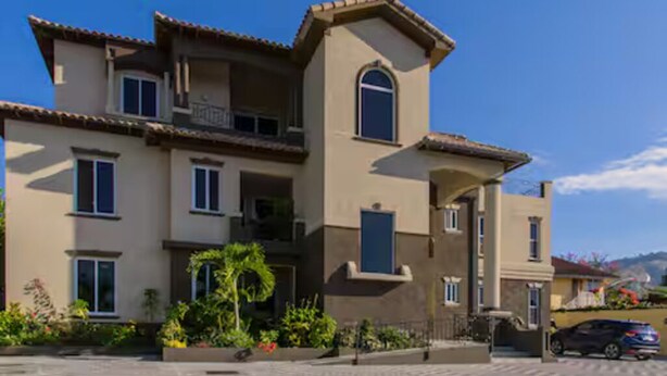 A multi-story house with a balcony, a driveway, and a parked car. - Star Tree- 2 Bedroom Condo 10 mins to New Kingston (Kingston)