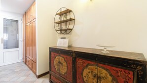 Um quarto com armários de madeira, uma prateleira decorativa e um aparador antigo com motivos florais.