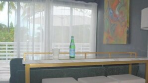 Eine Bar mit einer Theke, zwei gepolsterten Hocker, einer Flasche Limonade und einem Bild an der Wand.