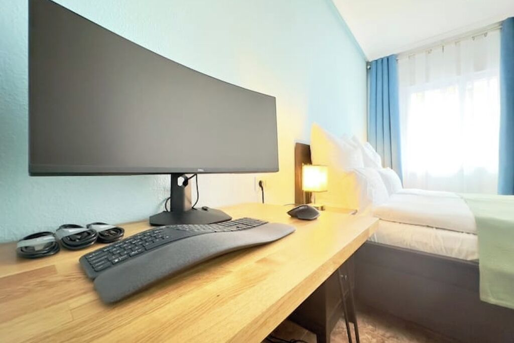 Une chambre d’hôtel équipée d’un bureau, d’un grand téléviseur à écran plat, d’un clavier et d’une souris.