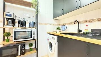 Cocina compacta con microondas, tostadora y lavadora.