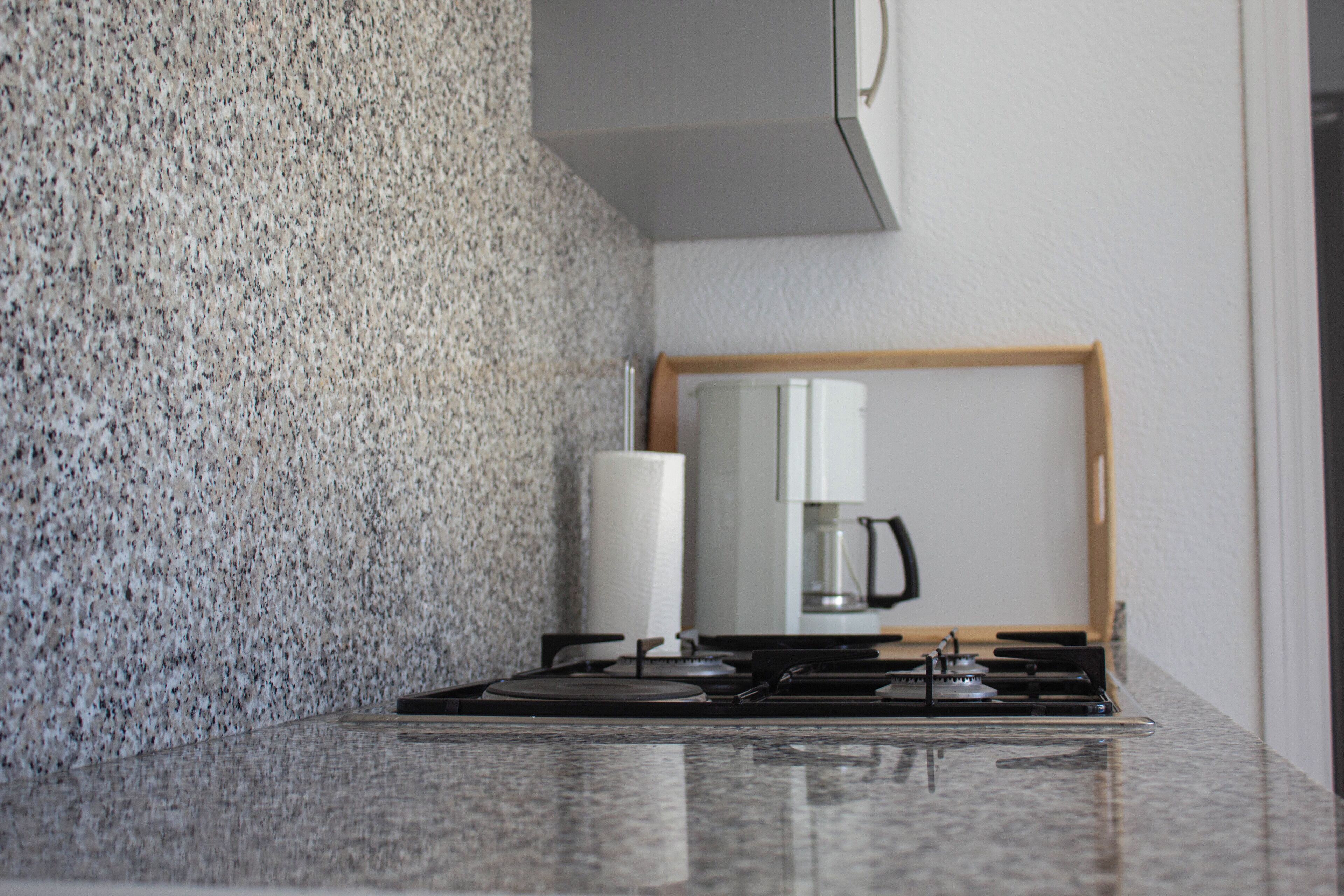A kitchen with granite countertops, a stove, and a coffee maker.