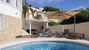 Ein Schwimmbecken mit Liegestühlen und einer Pergola.