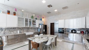 A modern kitchen with marble countertops, stainless steel appliances, and a dining area with a marble table and white chairs. - Elegant 4BR Marina Penthouse Private Pool (Dubai)